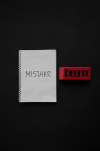 Flat lay of a notebook with 'Mistake' and red eraser labeled 'Delete', minimalist concept.