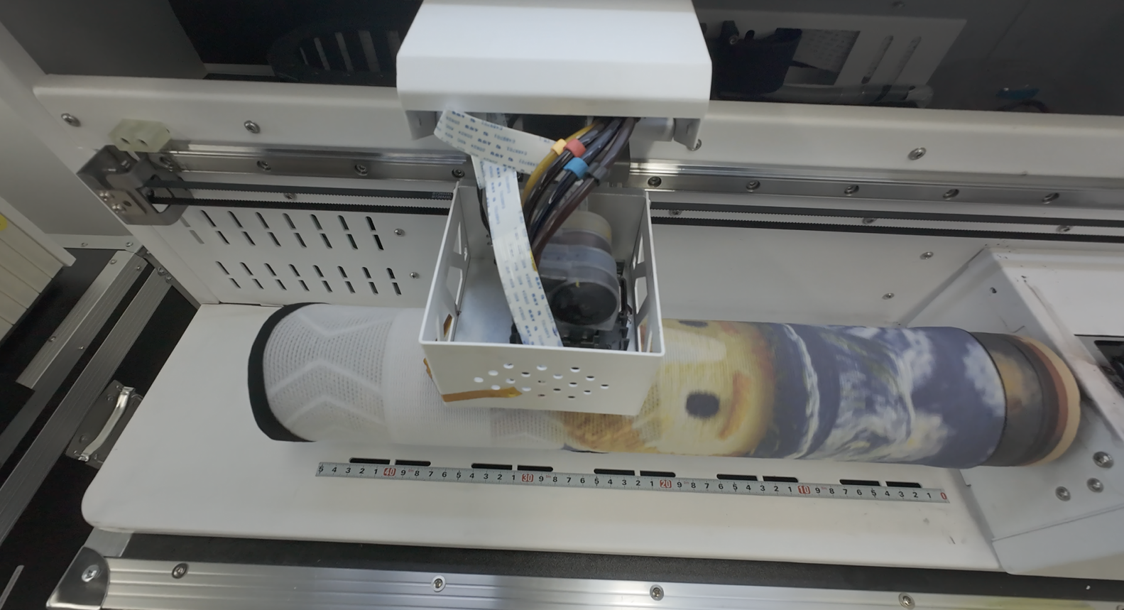 A 360 sock printer in action with the sock on the roller and the print head moving across